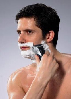 Homme utilisant un rasoir électrique avec de la crème à raser