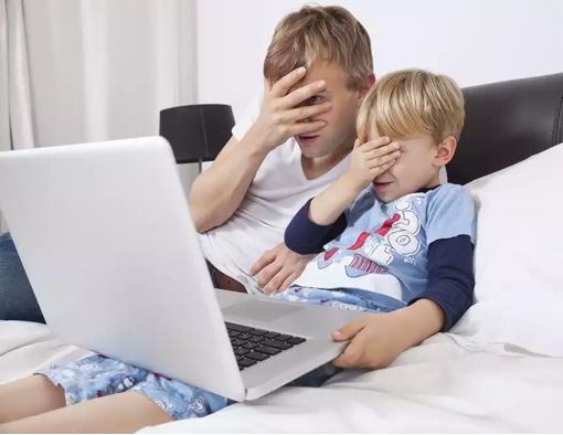 Un homme et un enfant cachent leurs yeux devant l'ordinateur